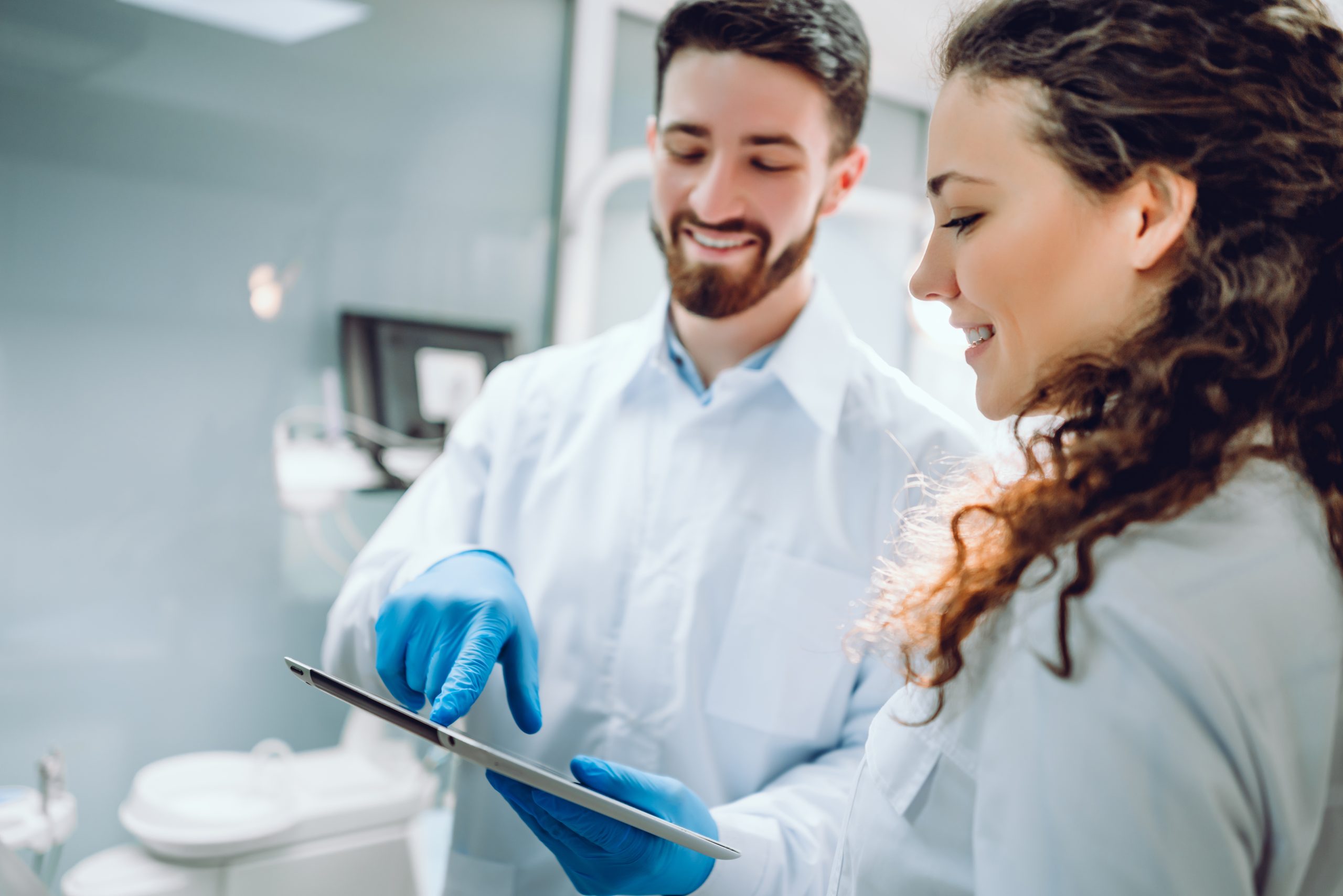 People, medicine, stomatology and health care concept   happy male dentist showing tablet pc computer to woman patient at dental clinic office.