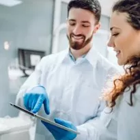 People, medicine, stomatology and health care concept   happy male dentist showing tablet pc computer to woman patient at dental clinic office.